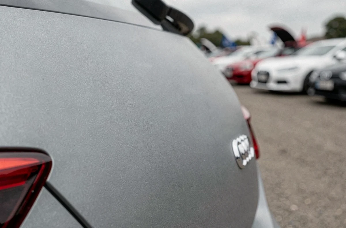 Gros plan macro sur la carrosserie en gris nardo LY7C d'une Audi, révélant la texture satin et la nuance froide caractéristique de cette teinte